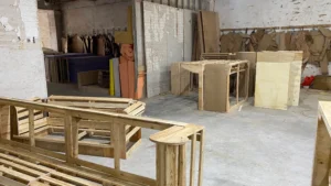 Handcrafted wooden furniture pieces, including tables and benches, in a carpentry workshop.